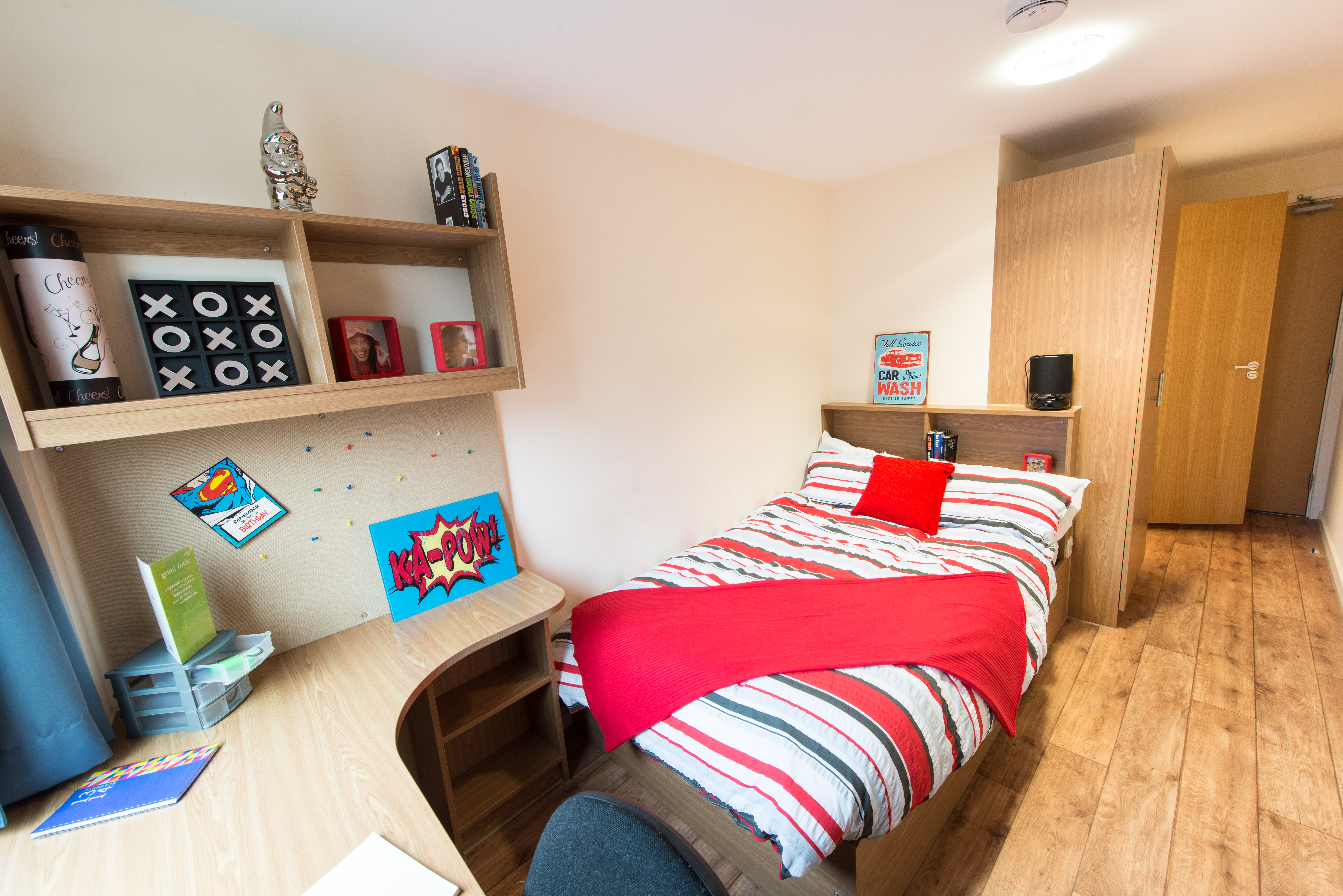 bedroom with a bed with red striped bedding in a university dorm